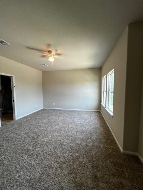 unfurnished room featuring ceiling fan, carpet floors, visible vents, and baseboards