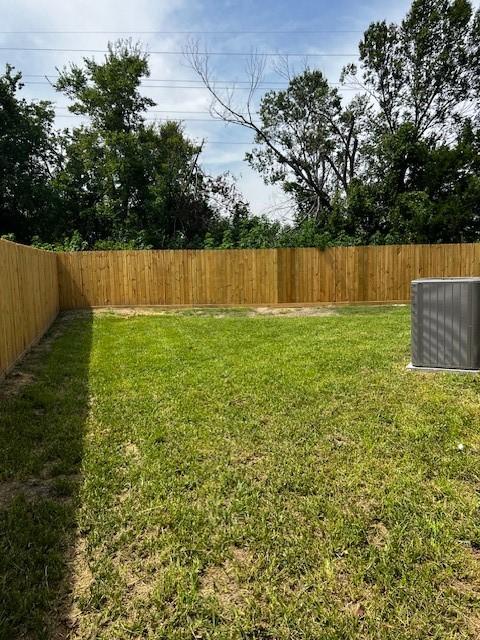 view of yard with a fenced backyard and central air condition unit