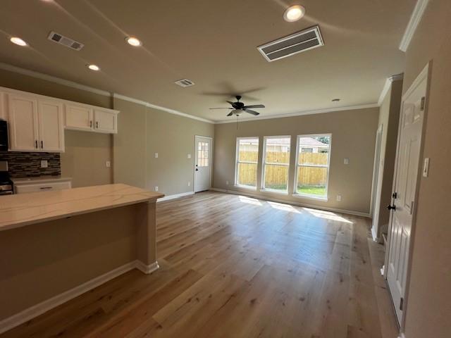 kitchen with decorative backsplash, visible vents, and crown molding