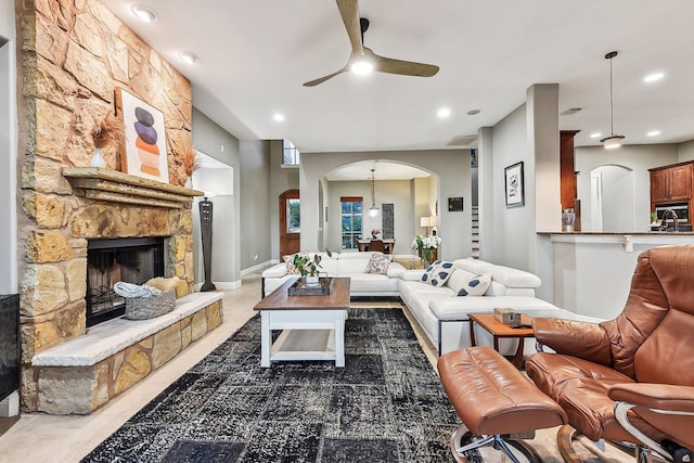 living area with arched walkways, a fireplace, a ceiling fan, and recessed lighting