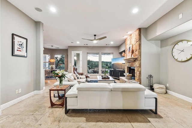 living area with a stone fireplace, recessed lighting, and baseboards