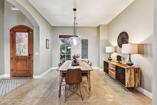 dining space featuring baseboards and arched walkways