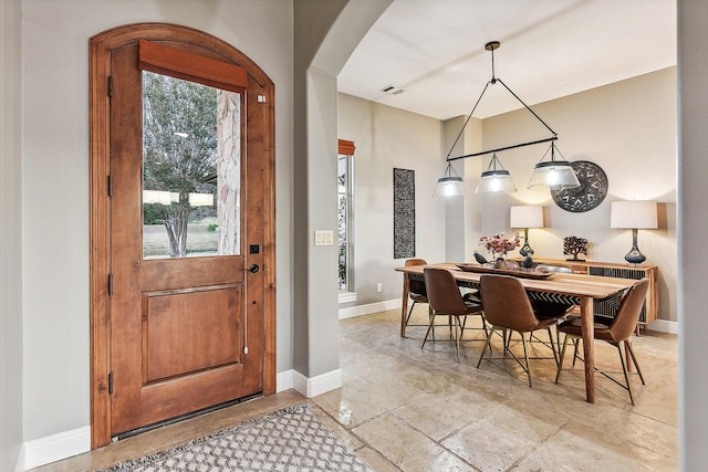 dining space with baseboards, visible vents, and arched walkways