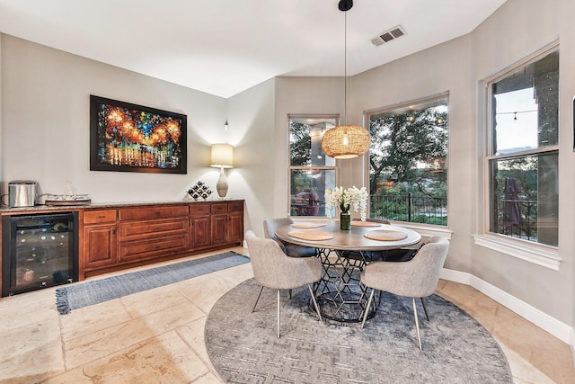 dining area with beverage cooler, a dry bar, visible vents, and baseboards