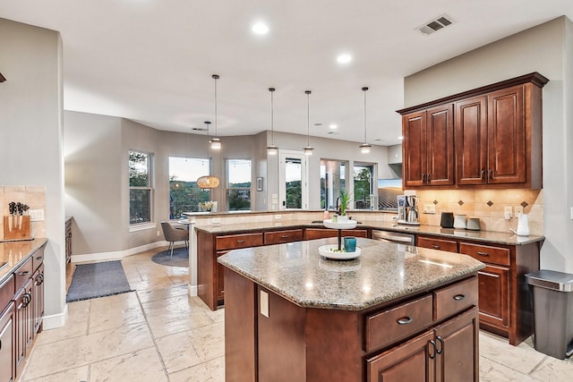 kitchen featuring stone tile flooring, visible vents, backsplash, a peninsula, and baseboards