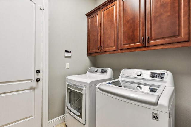 laundry room featuring separate washer and dryer, cabinet space, and baseboards