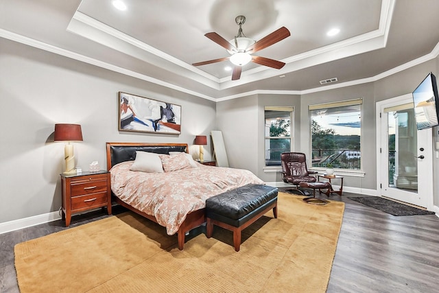 bedroom featuring baseboards, visible vents, a raised ceiling, ornamental molding, and dark wood-style flooring