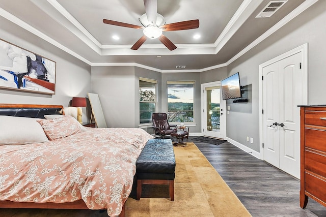 bedroom with visible vents, dark wood finished floors, baseboards, ornamental molding, and a tray ceiling