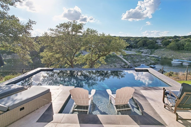 view of pool with a patio area, fence, a fenced in pool, and a water view