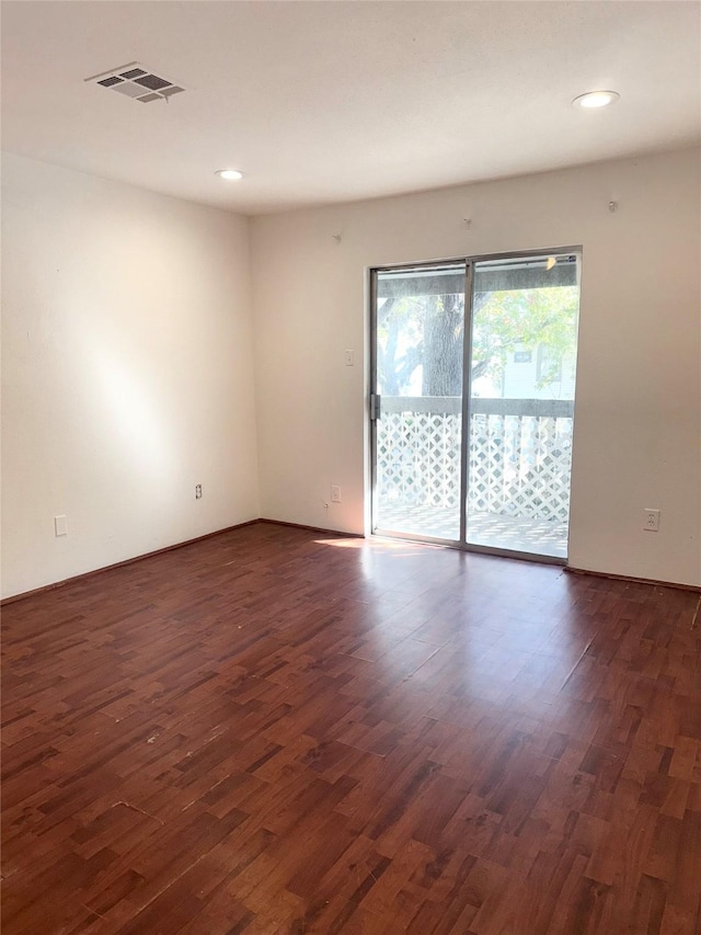 empty room featuring dark wood-type flooring, visible vents, and recessed lighting