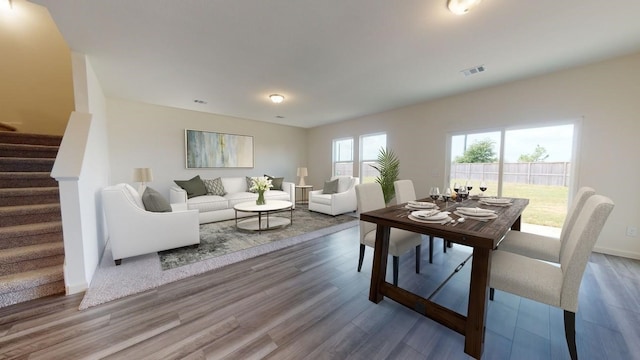 dining room with wood finished floors, visible vents, baseboards, and stairs