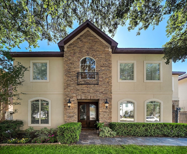 view of front facade with stone siding, french doors, and stucco siding