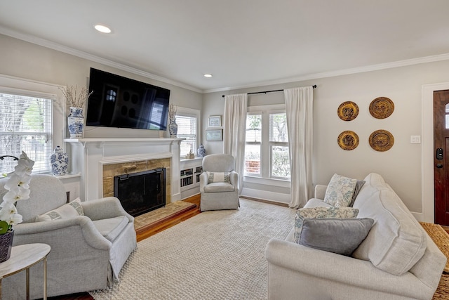 living area with ornamental molding, a healthy amount of sunlight, a fireplace, and wood finished floors