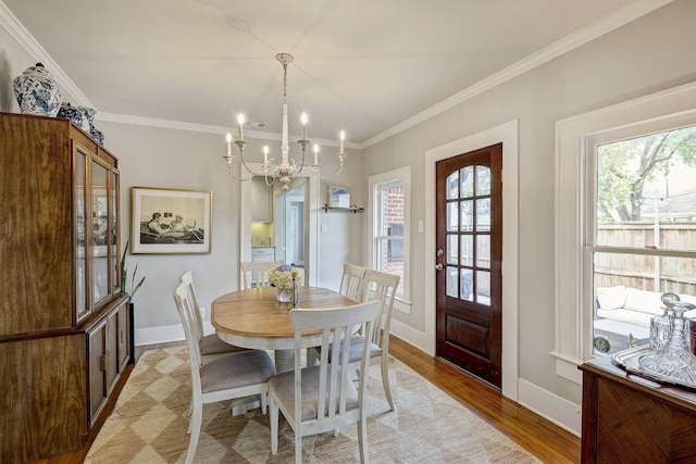 dining space featuring a notable chandelier, light wood finished floors, baseboards, and crown molding