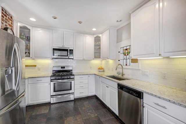 kitchen with stainless steel appliances, white cabinets, a sink, and decorative backsplash