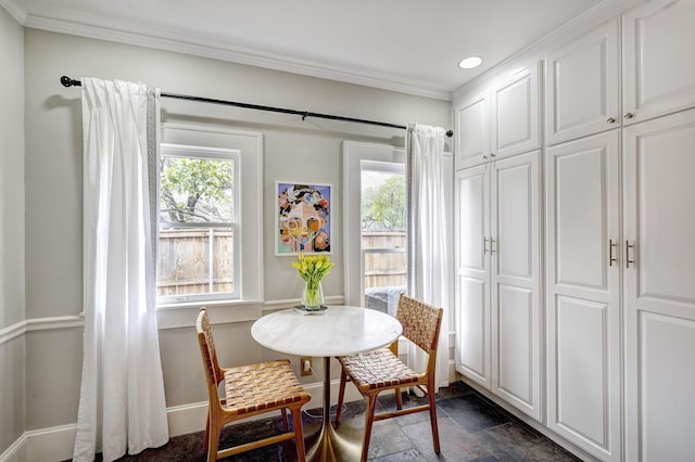 dining space featuring baseboards, crown molding, stone finish floor, and a wealth of natural light