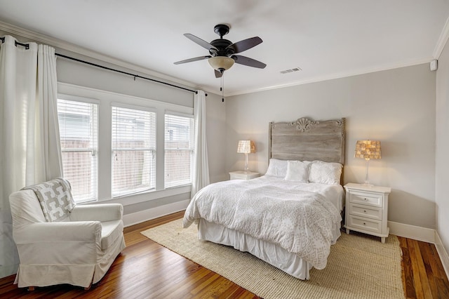 bedroom featuring visible vents, crown molding, baseboards, and wood finished floors