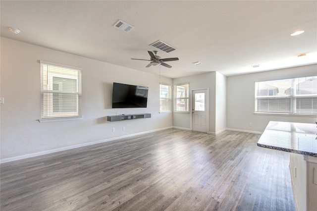 unfurnished living room featuring baseboards, visible vents, and wood finished floors