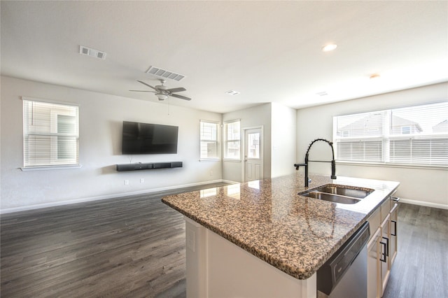 kitchen with dark stone countertops, visible vents, dishwasher, and a sink