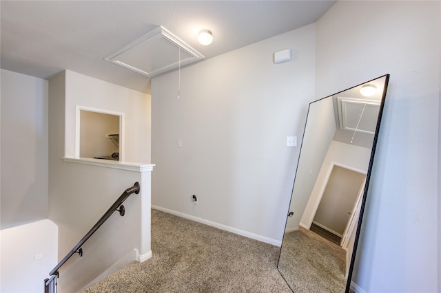 hallway with carpet flooring, an upstairs landing, attic access, and baseboards