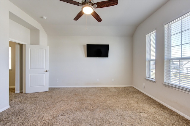 empty room featuring a wealth of natural light, vaulted ceiling, and carpet