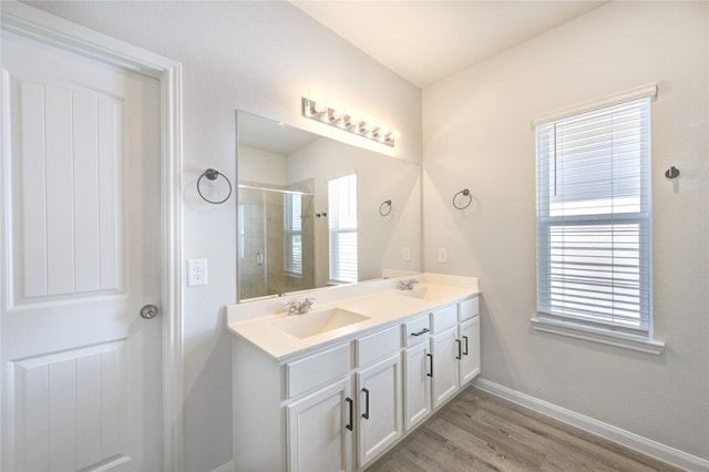 full bath featuring a sink, a shower stall, baseboards, and double vanity