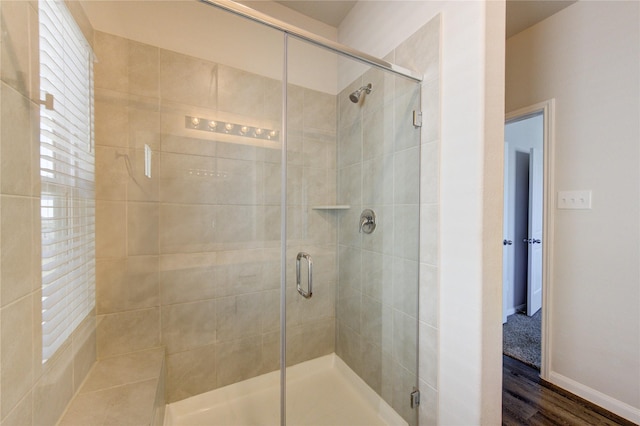 full bath featuring a shower stall, baseboards, and wood finished floors