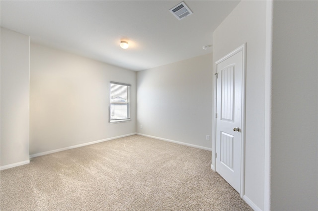 unfurnished room with carpet, visible vents, and baseboards