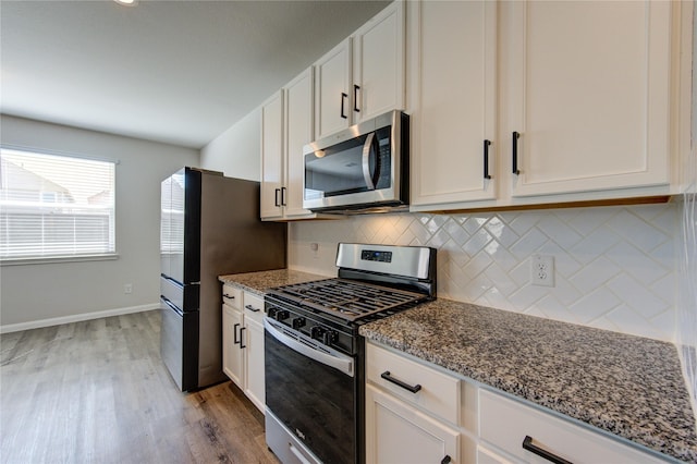 kitchen with tasteful backsplash, appliances with stainless steel finishes, and dark stone counters