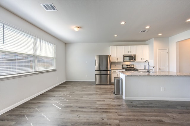 kitchen with stainless steel appliances, white cabinetry, visible vents, and baseboards