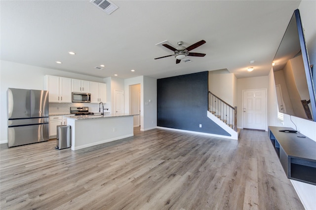 kitchen with stainless steel appliances, visible vents, light wood-style flooring, open floor plan, and white cabinetry