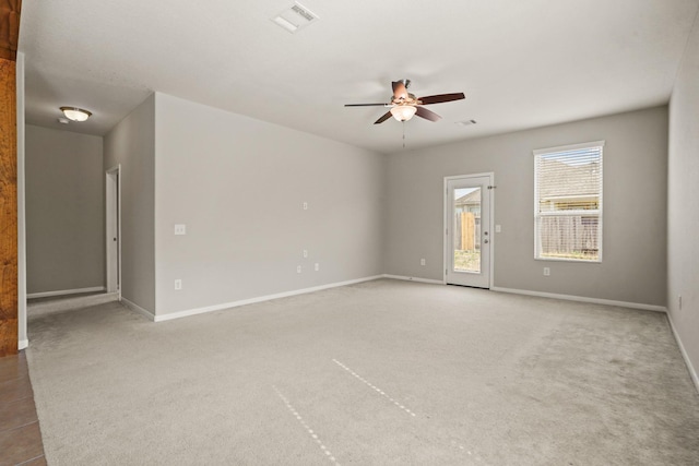 unfurnished room with a ceiling fan, light carpet, visible vents, and baseboards