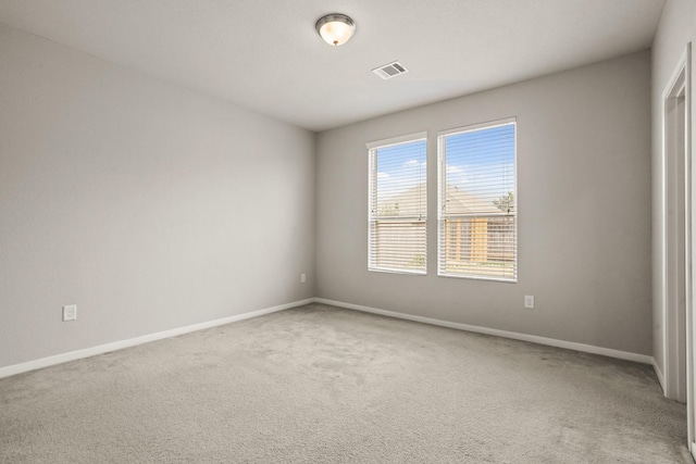 empty room featuring carpet, visible vents, and baseboards