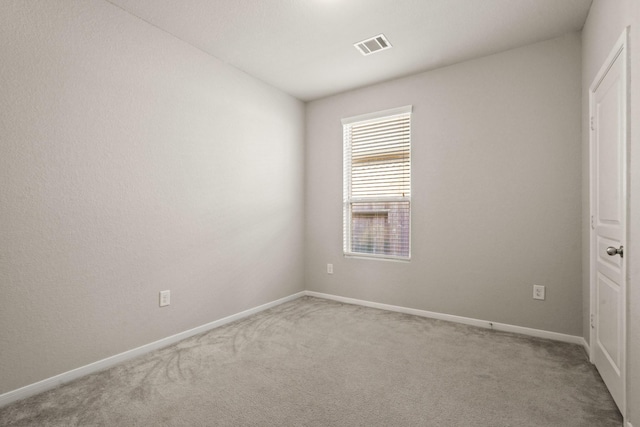 empty room with carpet, visible vents, and baseboards