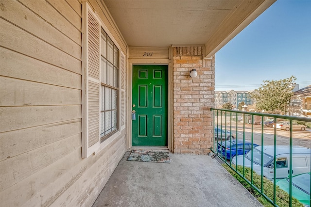 view of exterior entry with a balcony and stone siding