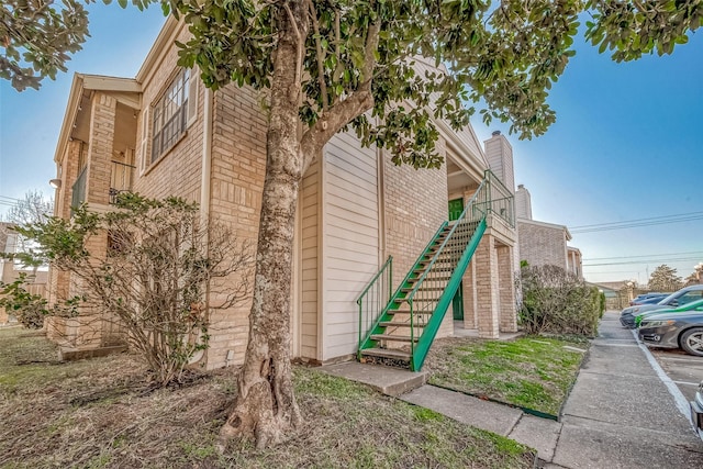 view of property exterior featuring stairway and brick siding