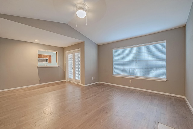 spare room featuring lofted ceiling, light wood-style floors, ceiling fan, and baseboards