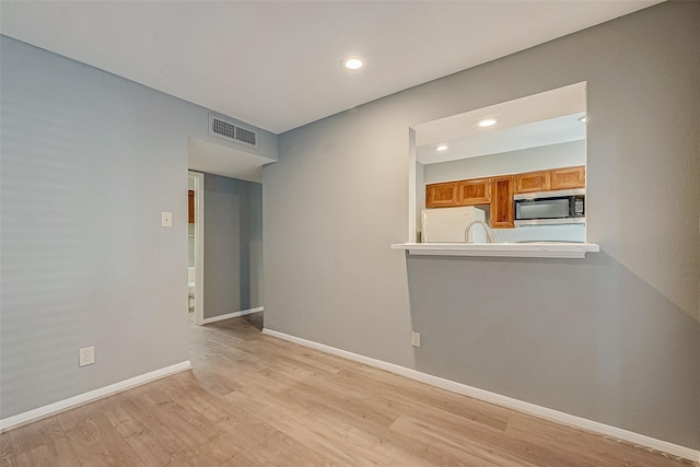 empty room featuring light wood-style floors, recessed lighting, visible vents, and baseboards