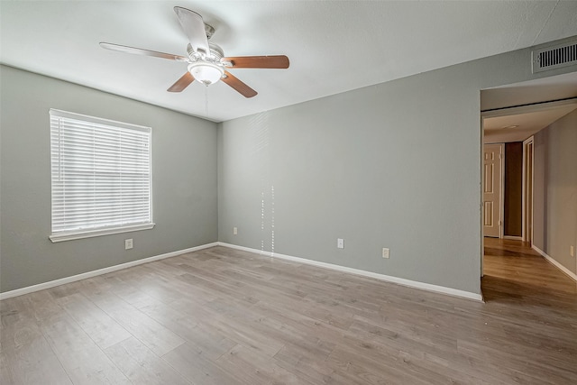 spare room with a ceiling fan, visible vents, light wood-style flooring, and baseboards