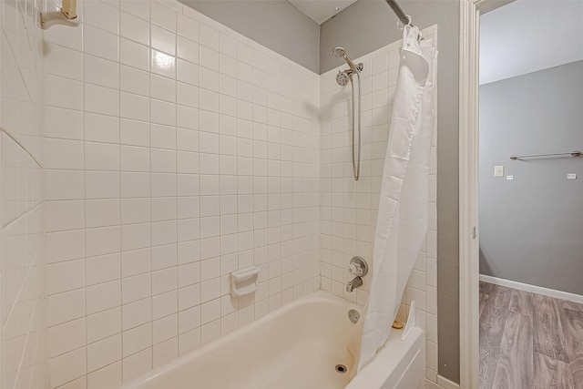 bathroom featuring baseboards, shower / tub combo with curtain, and wood finished floors