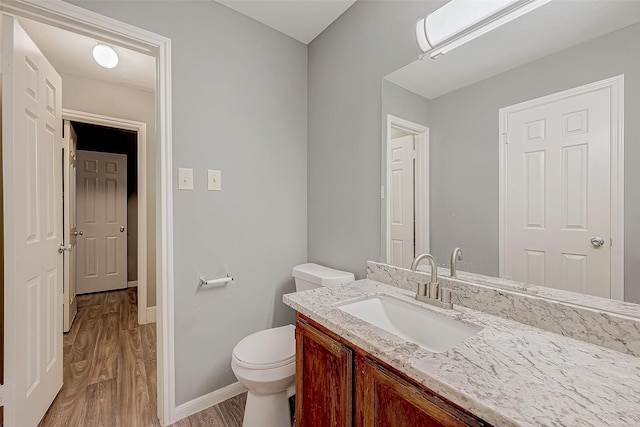 bathroom featuring vanity, wood finished floors, toilet, and baseboards