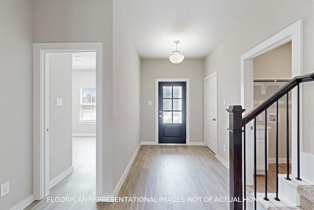 entrance foyer featuring baseboards, stairway, and wood finished floors