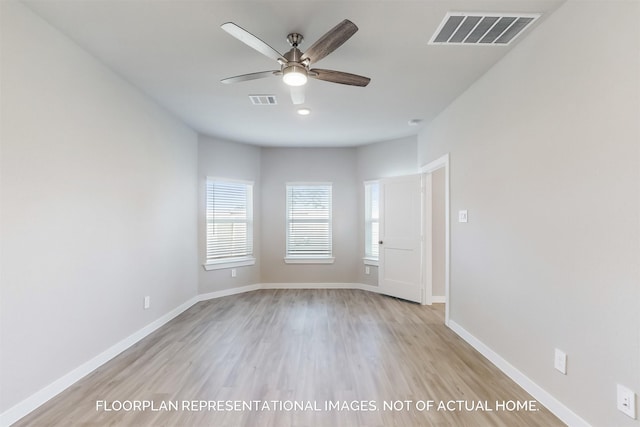 empty room with visible vents, light wood finished floors, and baseboards