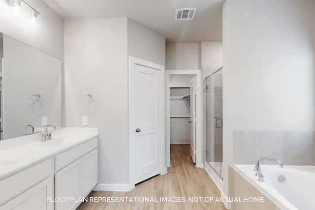 full bath with visible vents, a stall shower, a sink, wood finished floors, and a bath