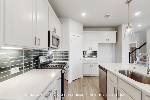 kitchen featuring a sink, visible vents, white cabinets, light countertops, and appliances with stainless steel finishes