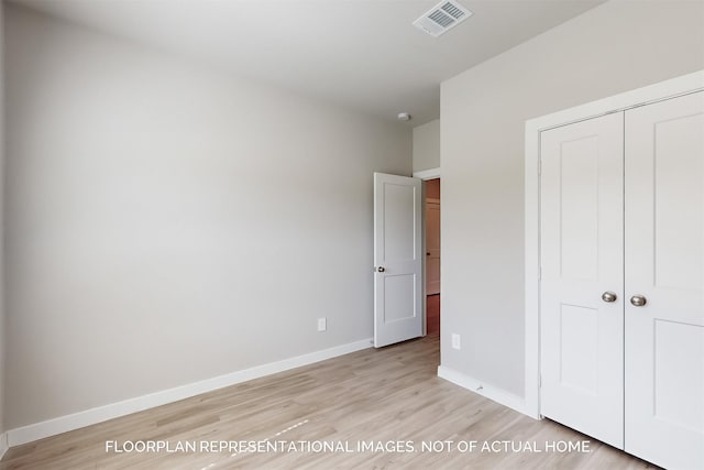 unfurnished bedroom with light wood finished floors, baseboards, visible vents, and a closet