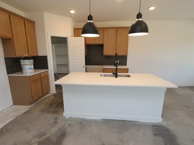 22427 Birchfield Grove Ln, New Caney, TX 77357 - kitchen featuring a sink, backsplash, concrete flooring, a kitchen island with sink, and brown cabinets