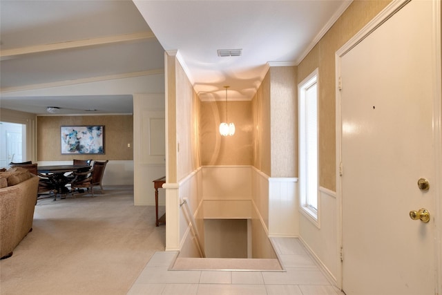 hallway featuring plenty of natural light, ornamental molding, carpet, and visible vents