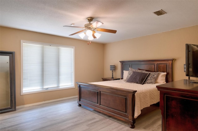 bedroom featuring light wood-type flooring, ceiling fan, and visible vents