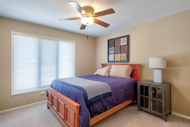 bedroom featuring a ceiling fan, light carpet, and baseboards